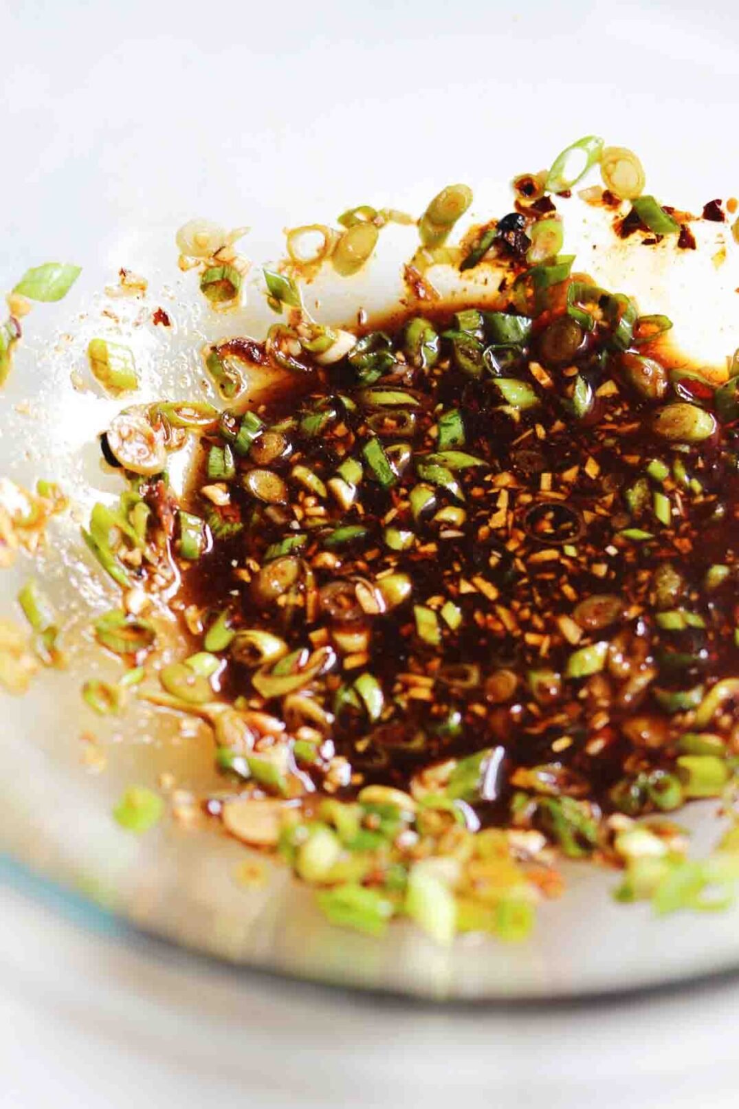 brown and green spicy garlic sauce in a clear glass bowl.