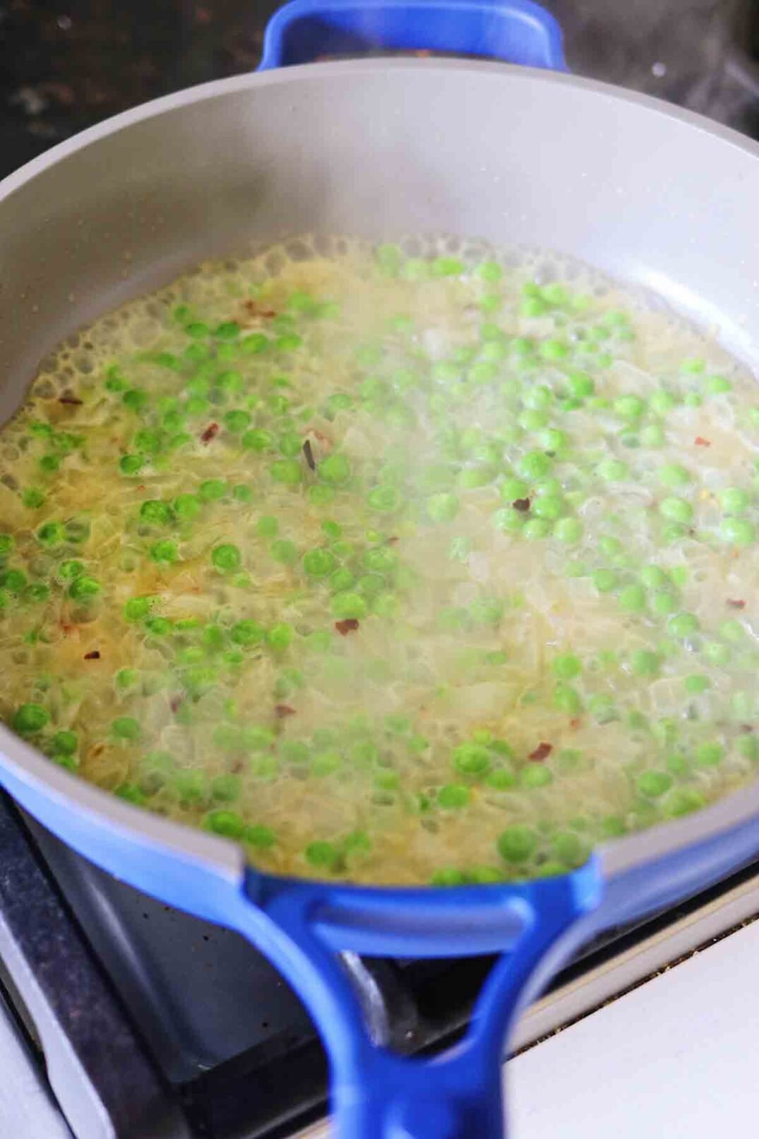 peas and onions cooking in a pan.