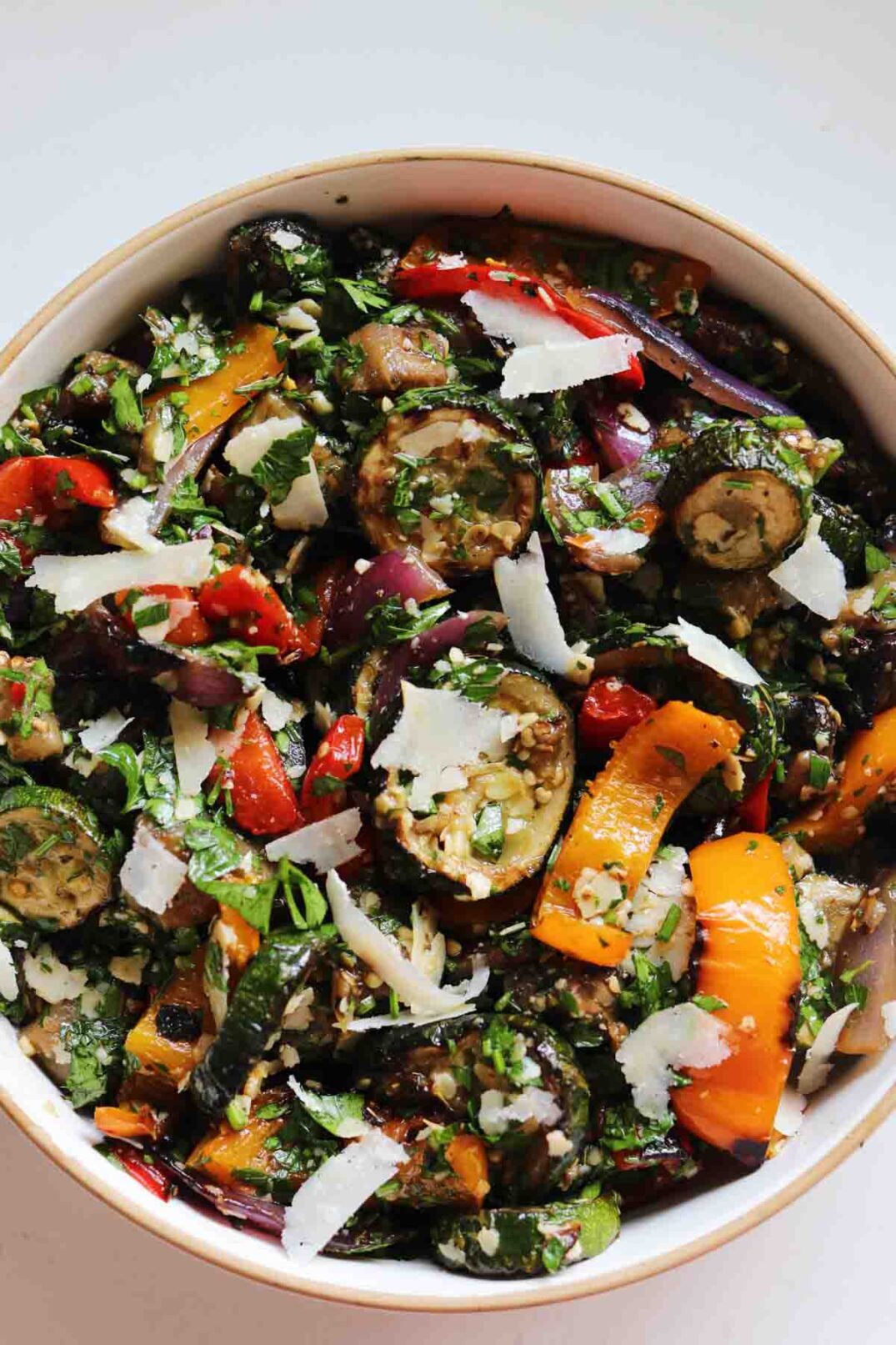 a bowl of colorful grilled vegetables tossed in bright green chimichurri sauce.