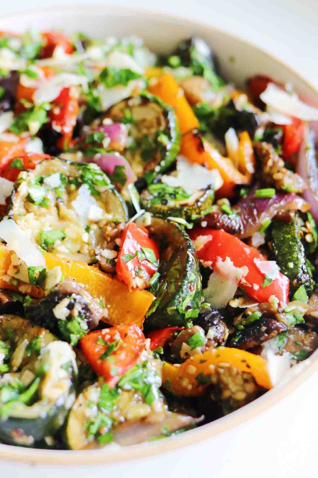 a white bowl filled with colorful veggies tossed in green herb sauce.