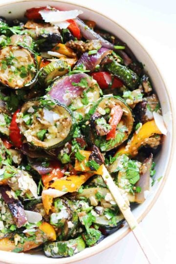 the right side of a white bowl filled with colorful veggies and green sauce.