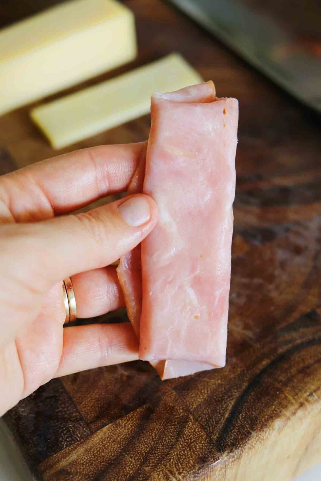 a hand holding a ham and cheese rollup.