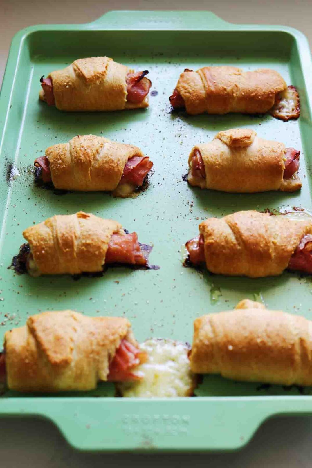 a sheetpan lined with golden brown ham and cheese crescent rolls fresh out of the oven.