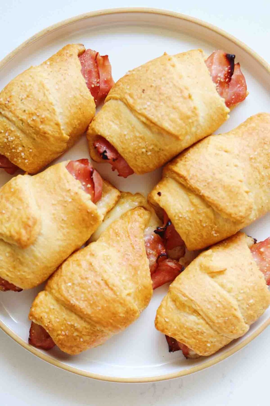 an overhead view of a plate of golden brown ham and cheese crescent rolls.