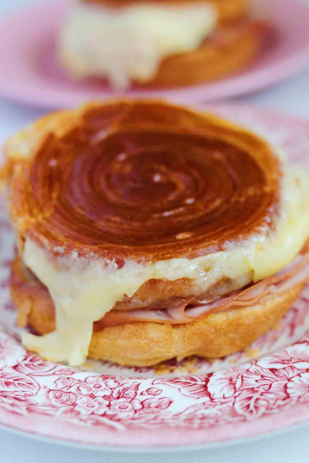 a close up of a croissant bun filled with comte cheese and hot ham.