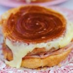 a close up of a croissant bun filled with comte cheese and hot ham.