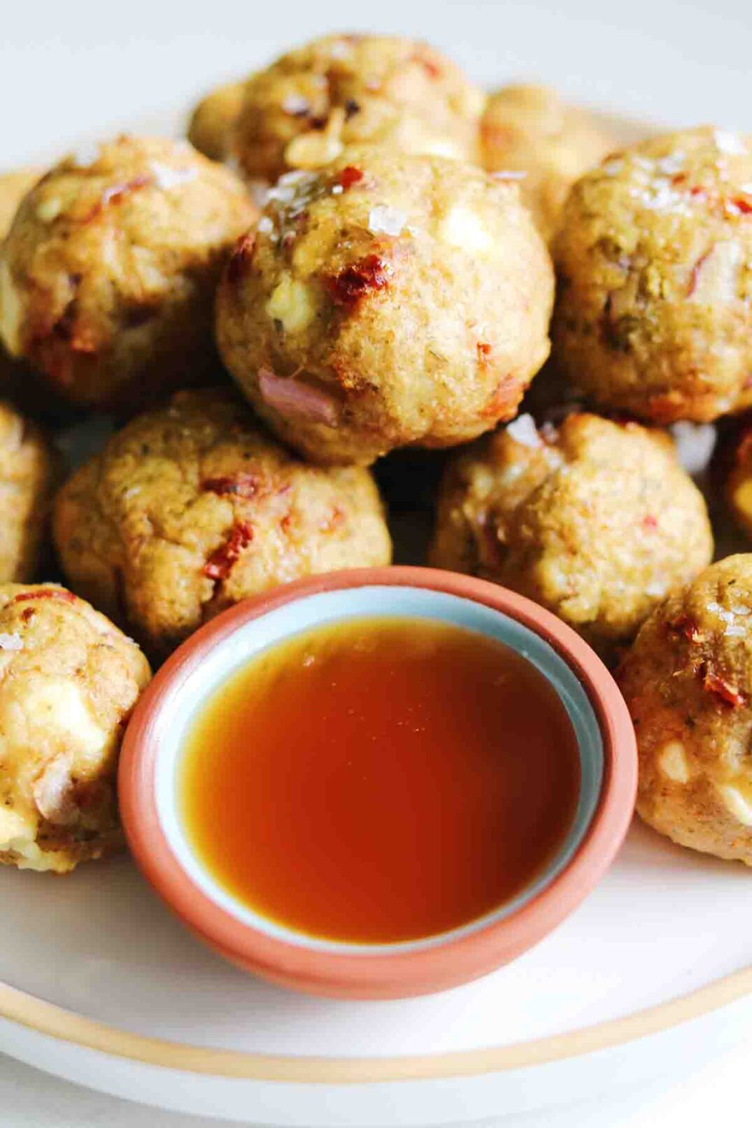 a pile of pesto chicken meatballs with a side of hot honey.