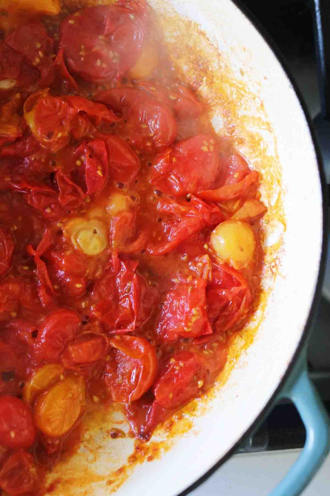 red burst cherry tomato sauce in a blue pot on the stovetop.
