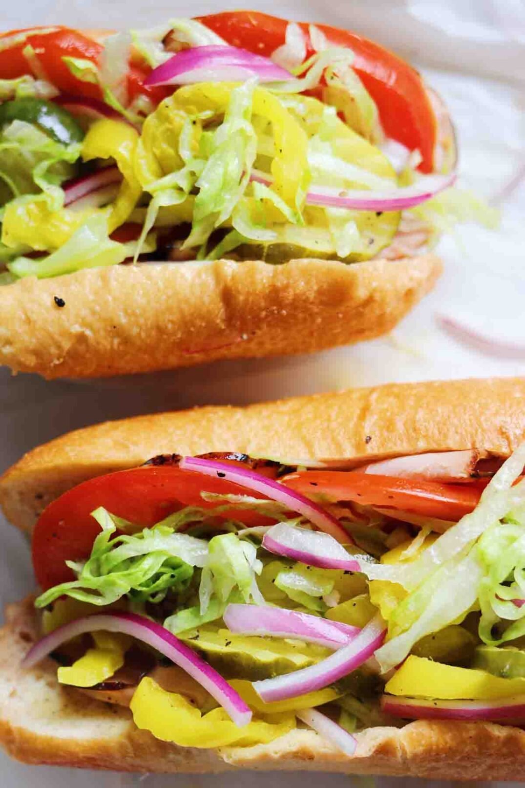 two halves of a turkey sub with colorful ingredients spilling out. 