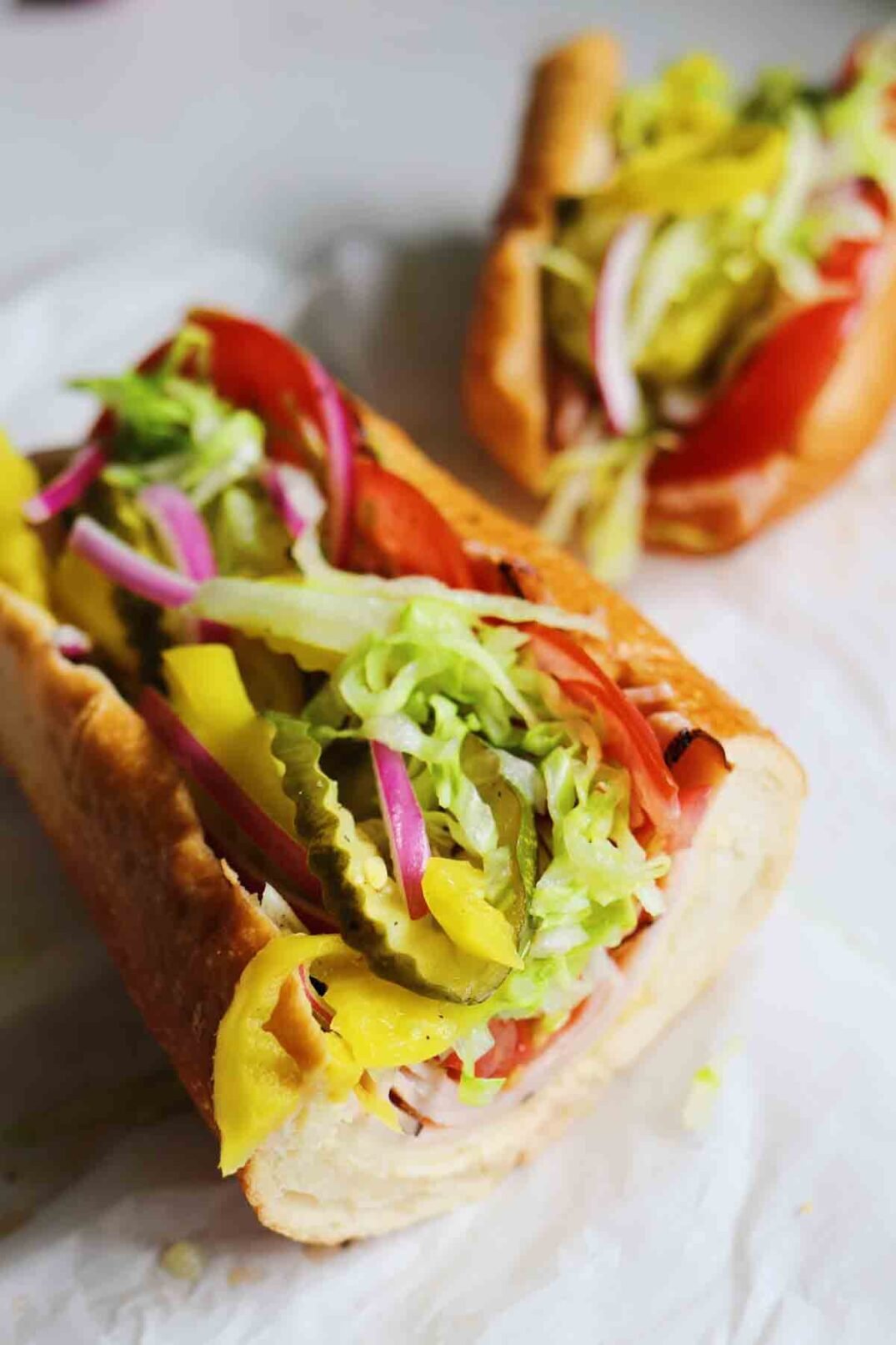 two halves of a colorful turkey sub on a piece of parchment paper.