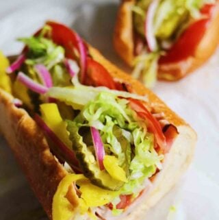 two halves of a colorful turkey sub on a piece of parchment paper.