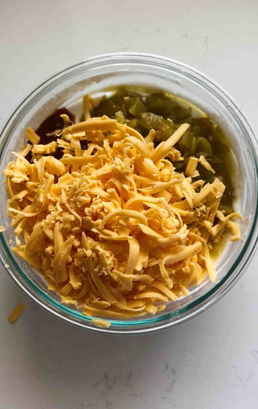 shredded cheese, hatch green chiles, hot sauce and whipped cottage cheese in a glass bowl.
