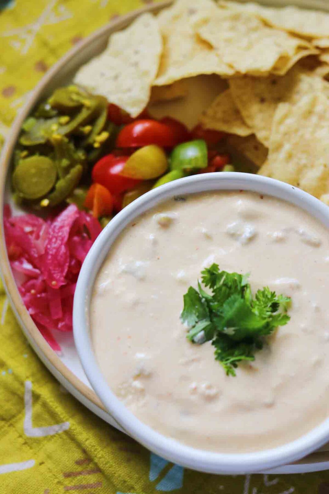 cottage cheese queso dip swirled with green hatch chiles on a green tablecloth.