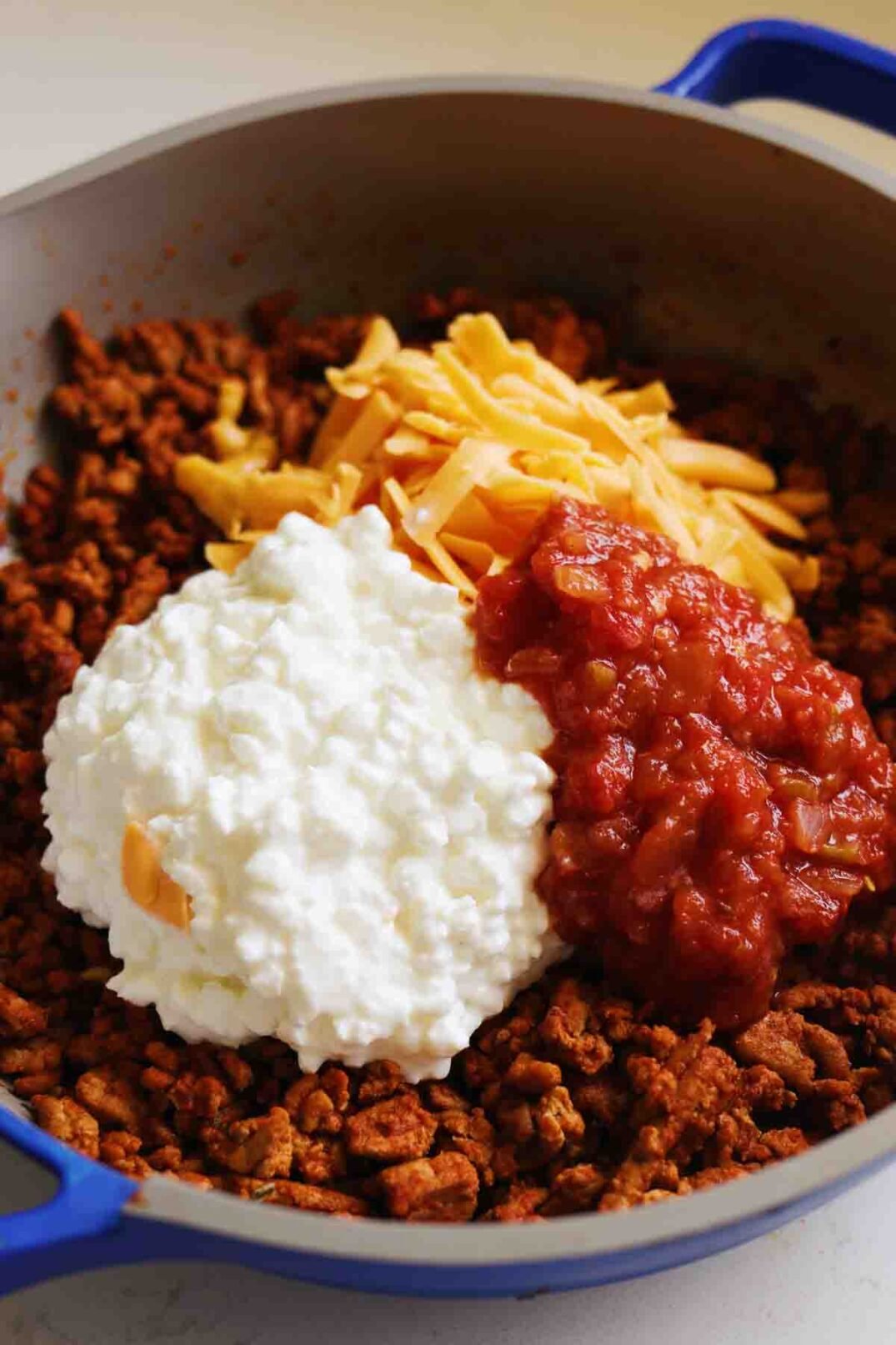 taco meat, cottage cheese, cheddar and salsa in a pot.