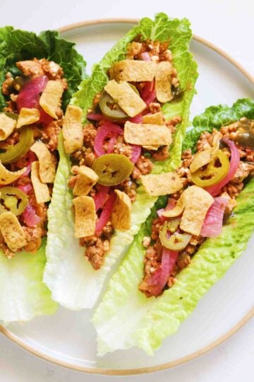cottage cheese walking taco in lettuce wraps on a white plate on a white countertop.