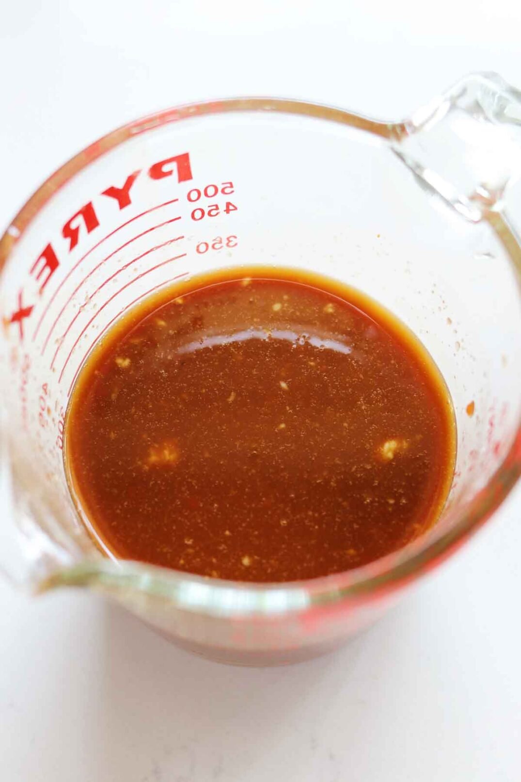 light brown bourboon sauce in a clear pyrex glass measuring cup. 