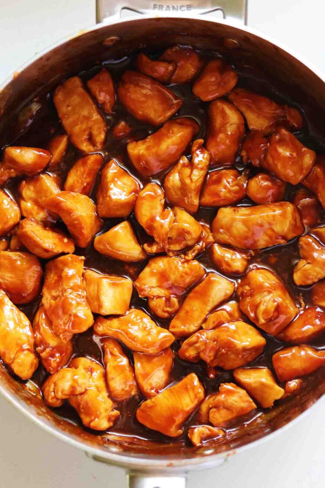 Honey Bourbon Chicken in a silver pan on a white countertop. 