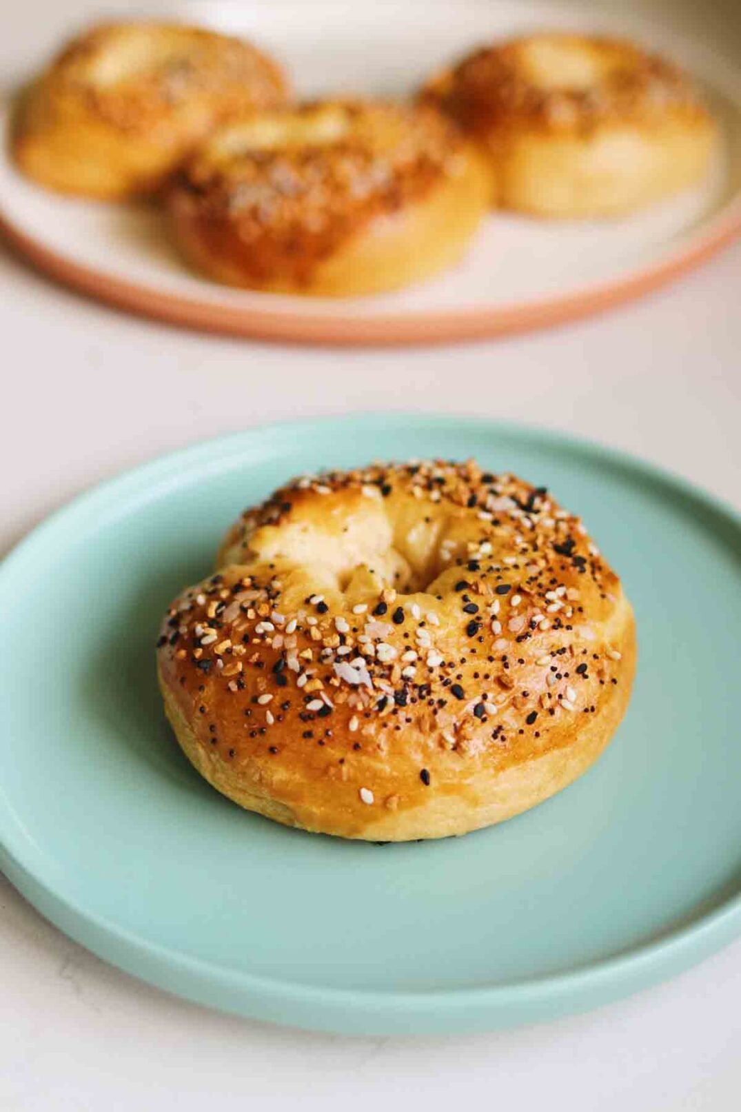 a single stuffed bagel sitting on a blue plate with other stuffed bagels in the background
