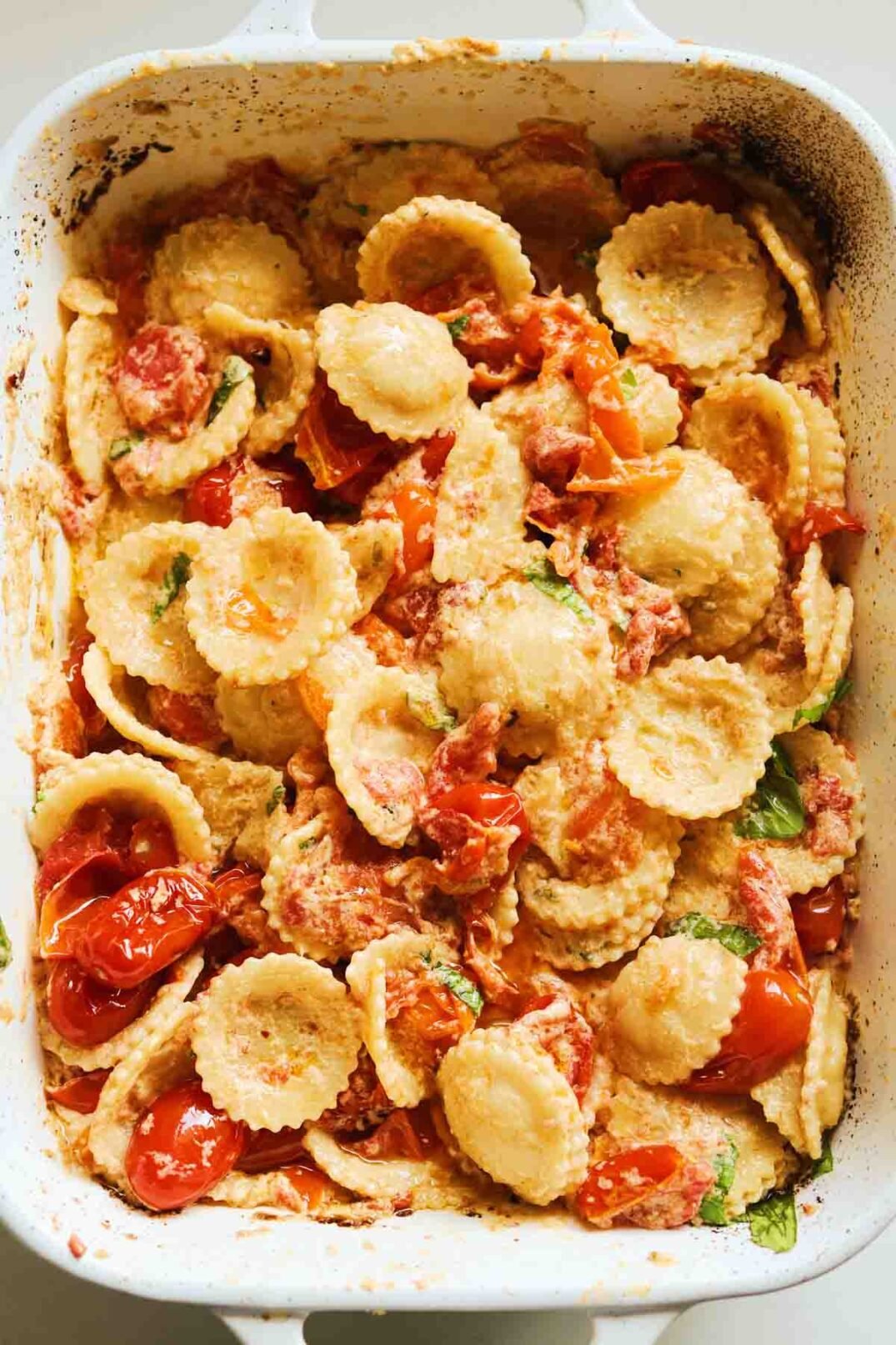 a big white staub baking dish full of burst tomatoes, pasta and creamy boursin cheese sauce.