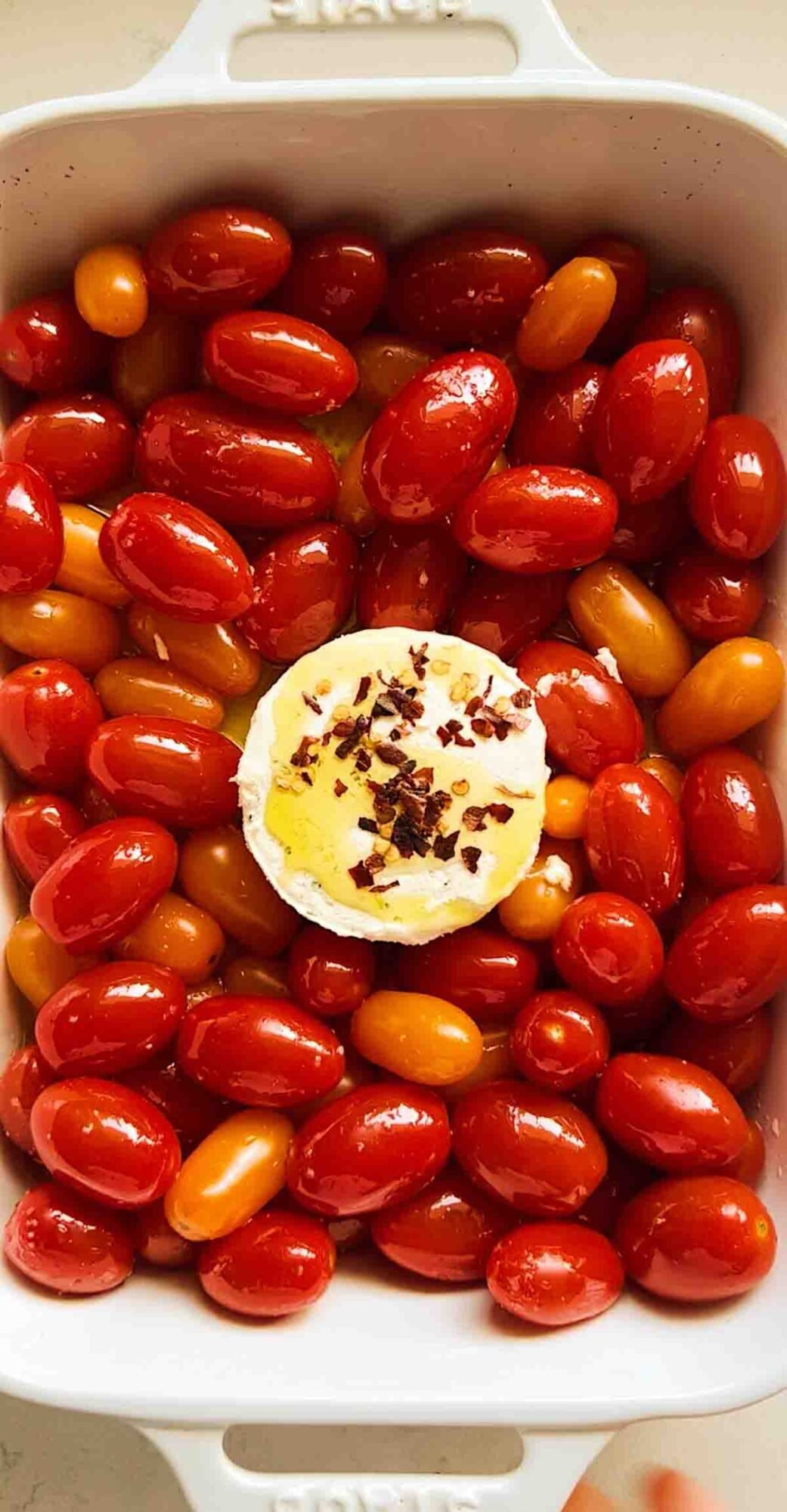 boursin cheese in the middle of cherry tomatoes with olive oil, salt and red pepper flakes.