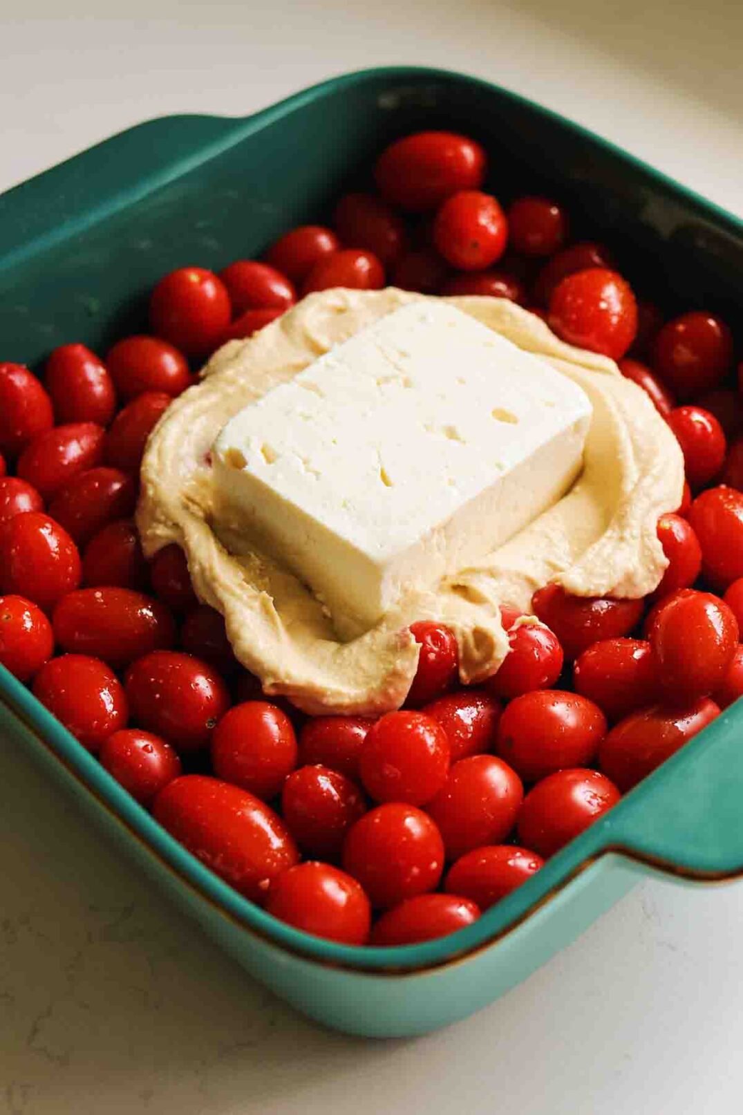 tomatoes, feta and hummus in a baking dish. 