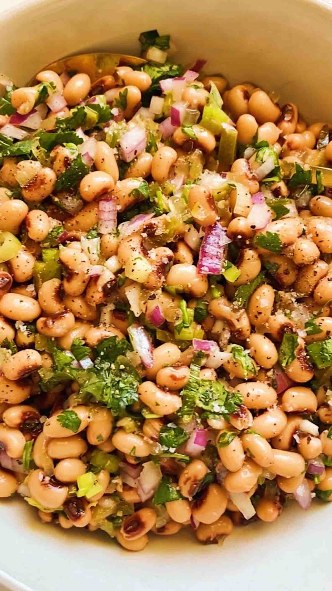 a white bowl filled with black eyed pea salad.