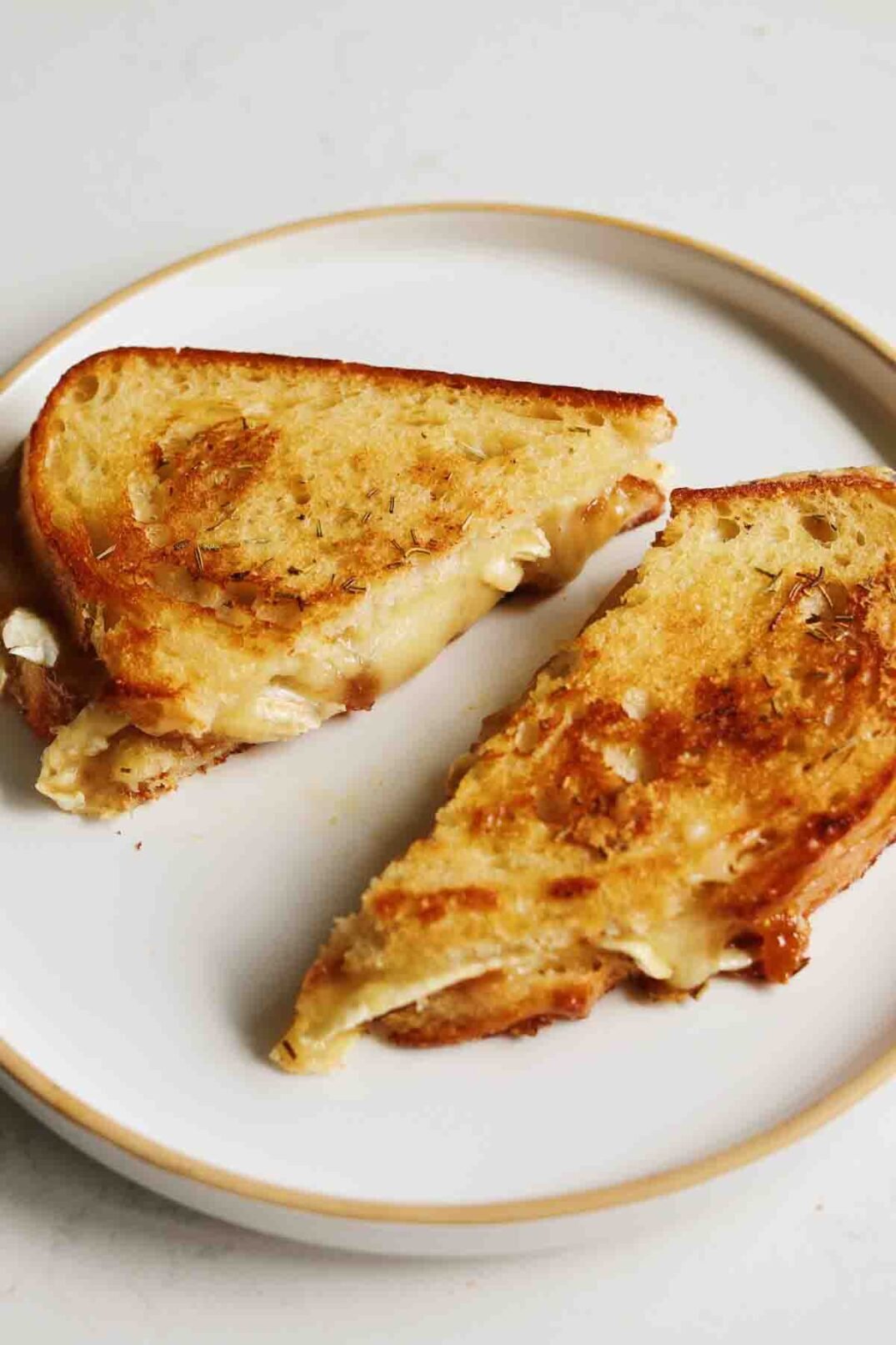 two halves of a brie grilled cheese with fig jam on a white plate. 