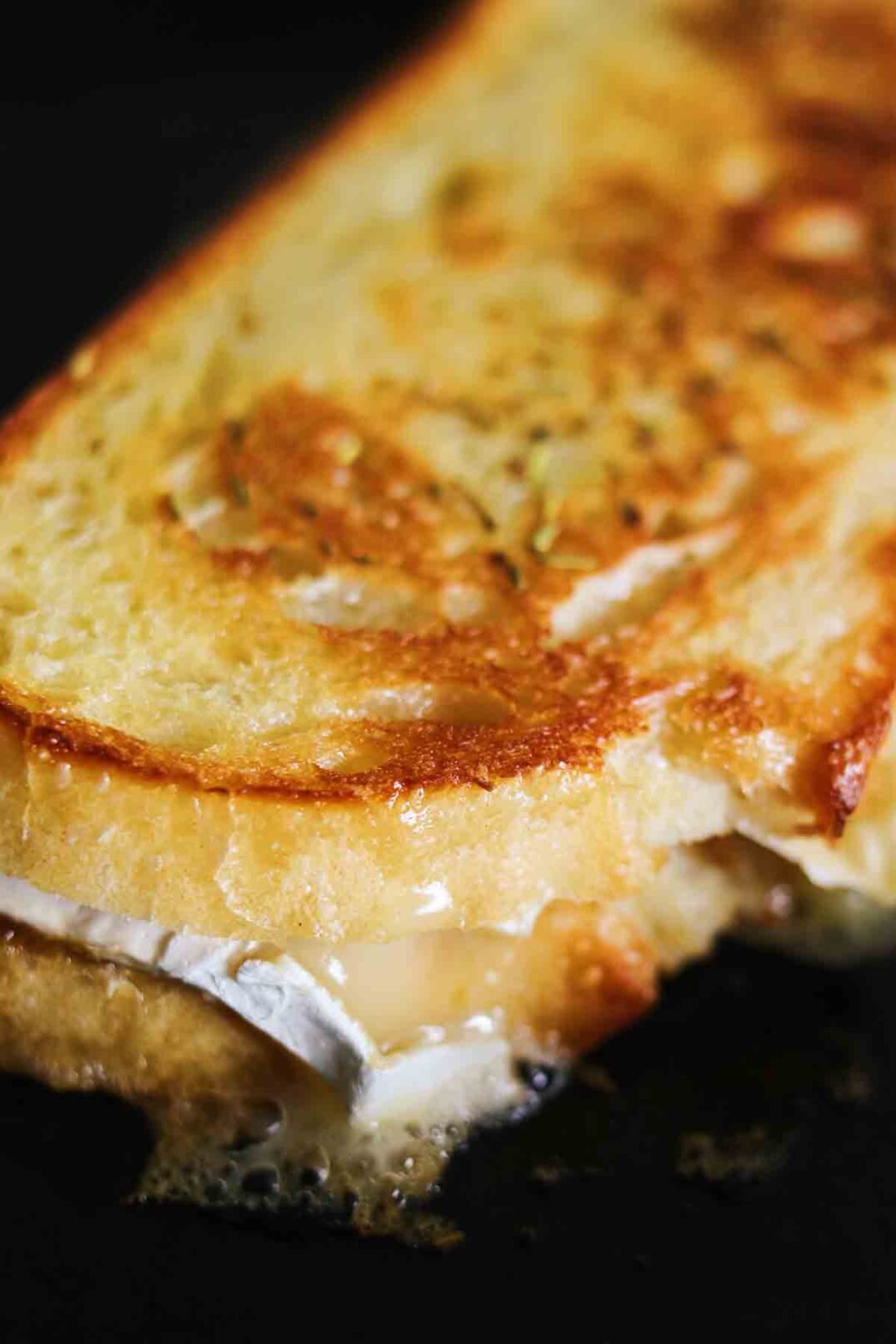 a gooey grilled cheese being griddled on a cast iron skillet.
