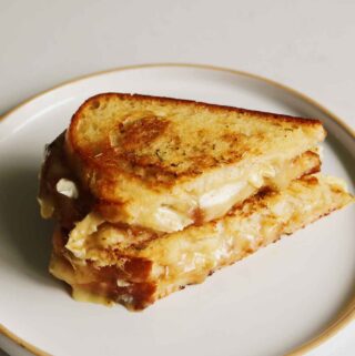 a brie grilled cheese sitting on a white plate.