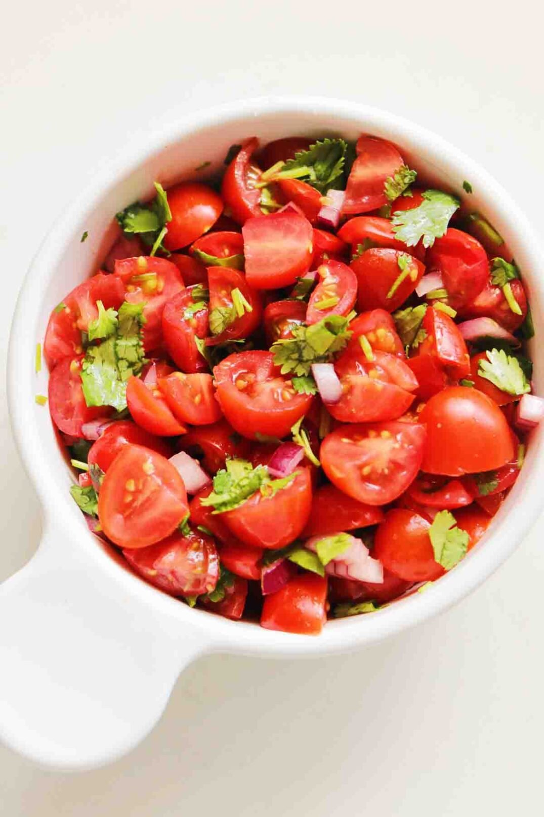 a white bowl of red cherry tomato salsa.