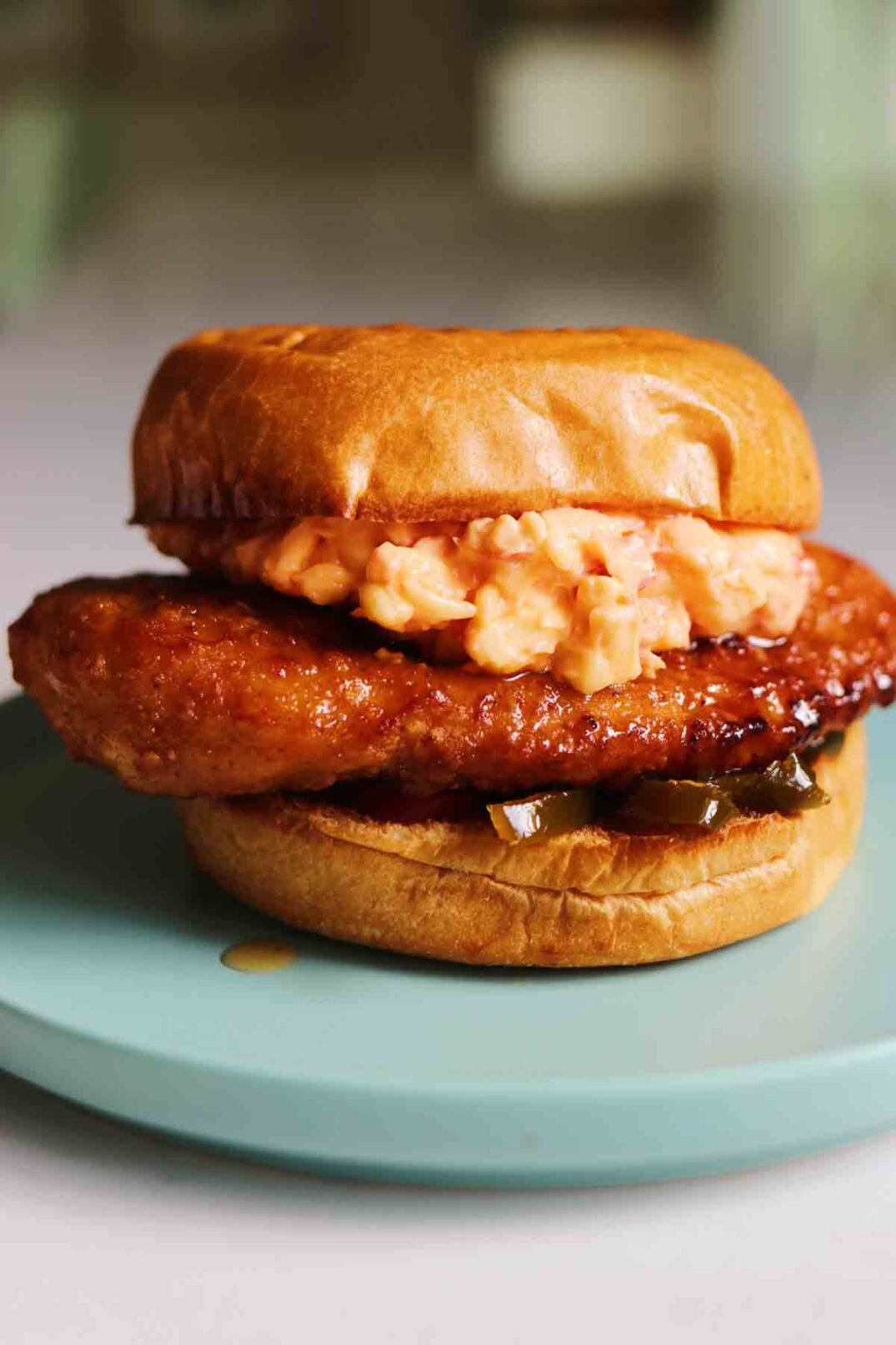 a blue plate with a Chick-fil-a Honey Pepper Pimento Chicken Sandwich Dupe sitting on top. 