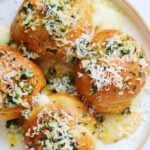 a plate full of Crescent Roll Garlic Knots with butter, garlic and cheese oozing out.