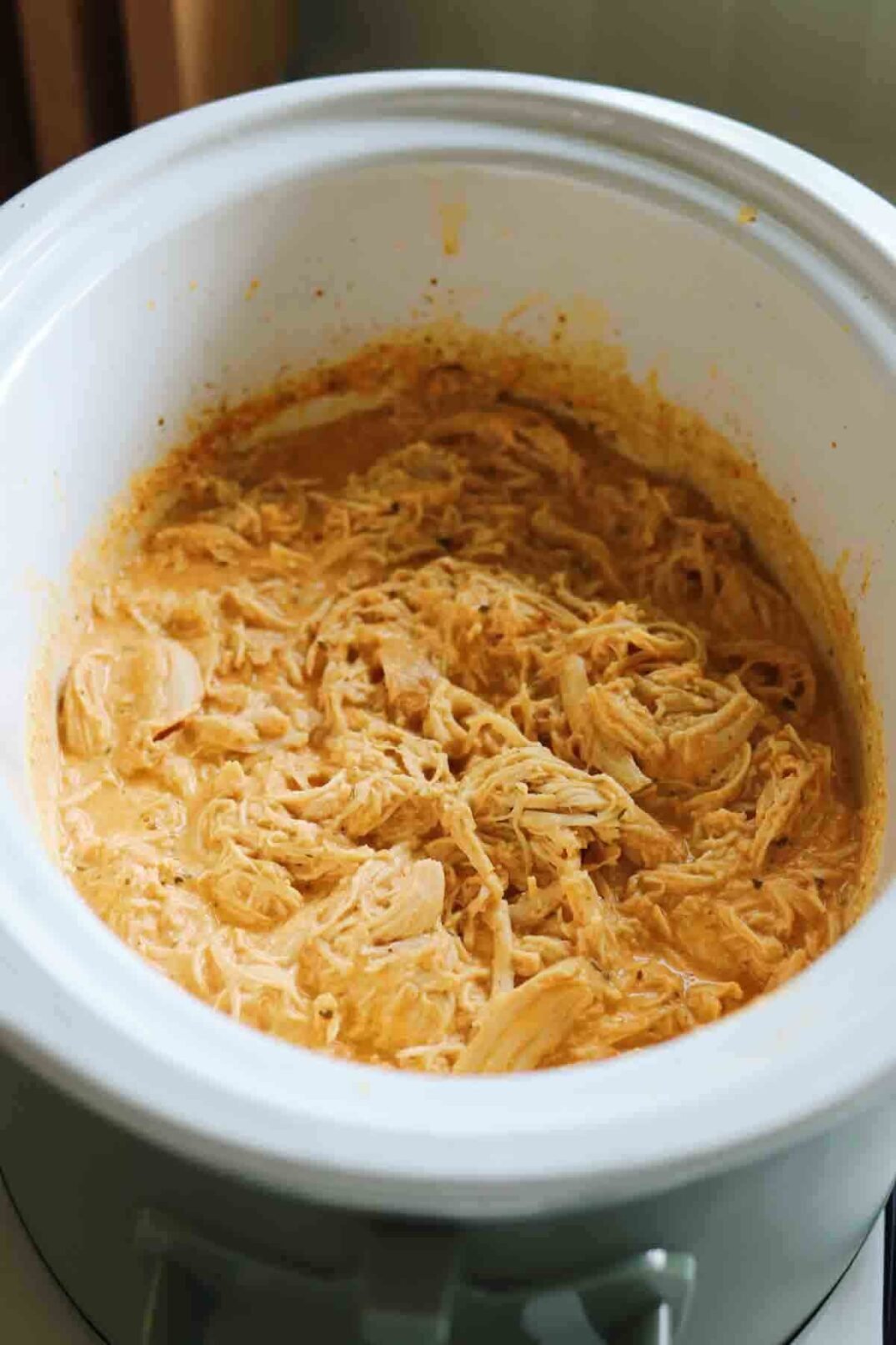 buffalo chicken dip in a slow cooker with shredded cheese.