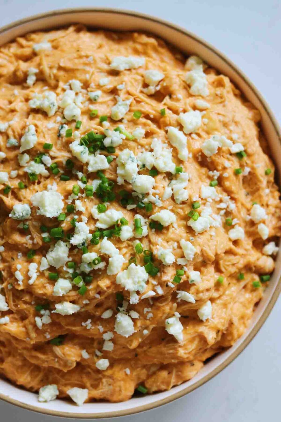 the right side of a white bowl filled with buffalo chicken dip .
