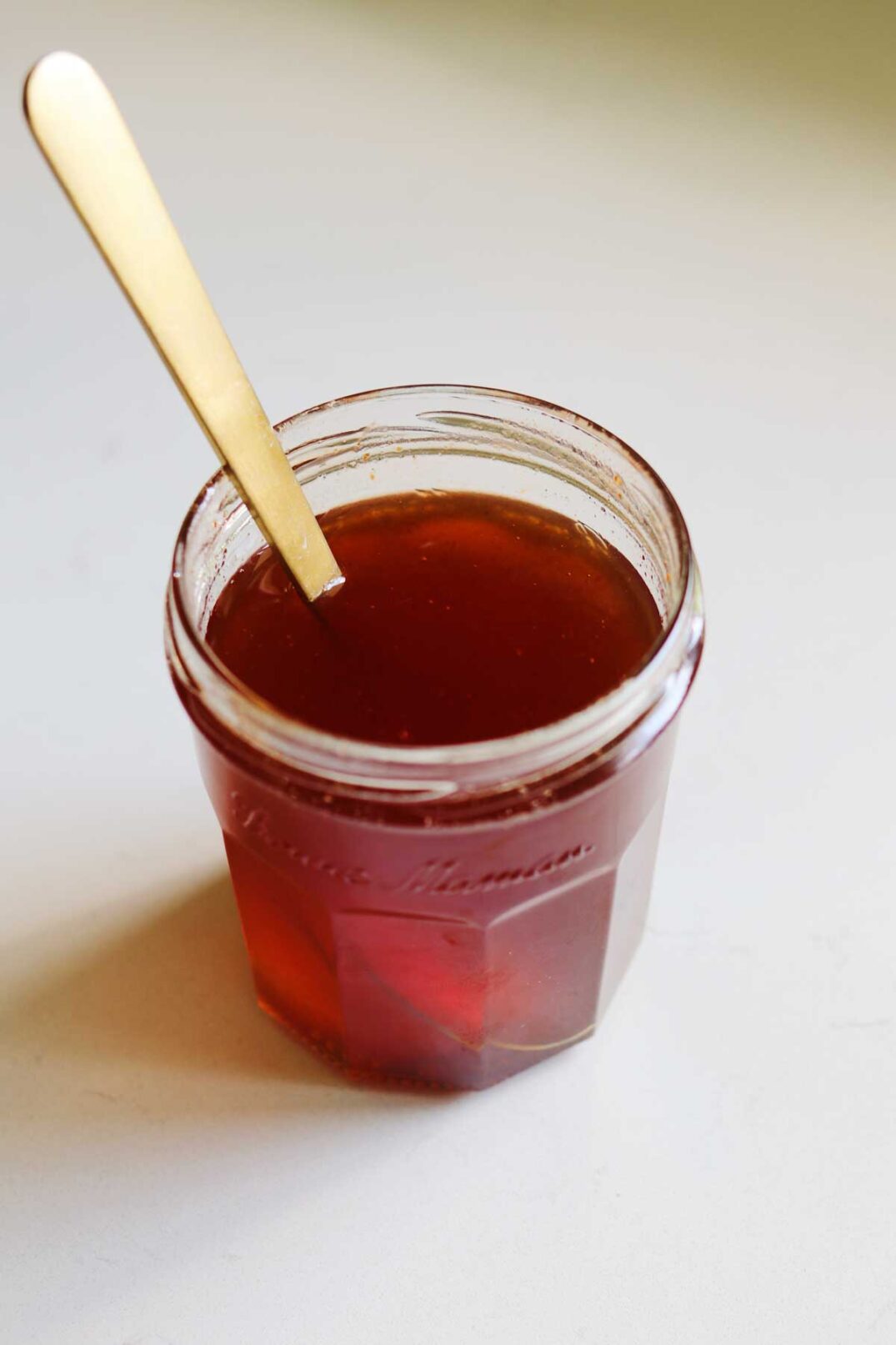 a clear glass jelly jar full of homemade hot honey sauce. 