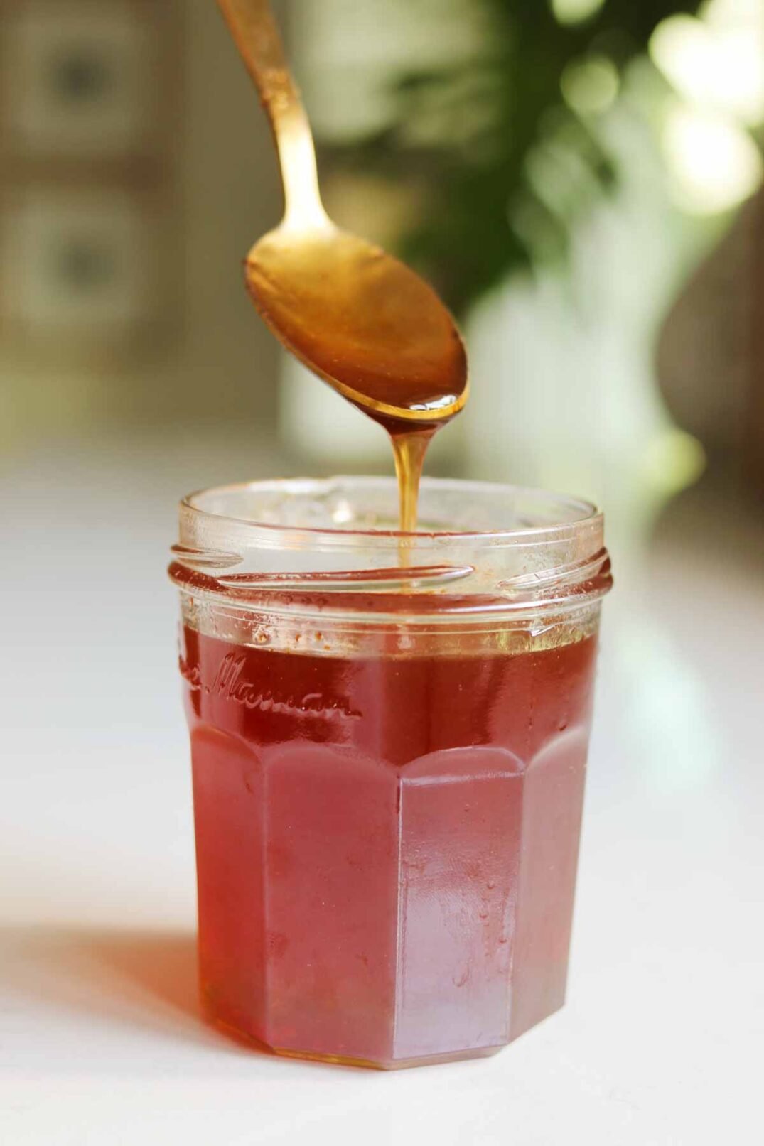hot honey sauce in a clear jar with a golden spoon pouring a drizzle.