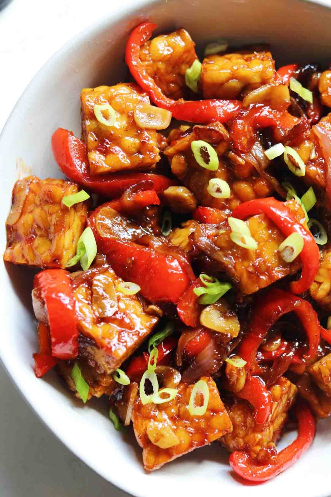 a white bowl full of sweet and spicy glazed crispy tempeh.