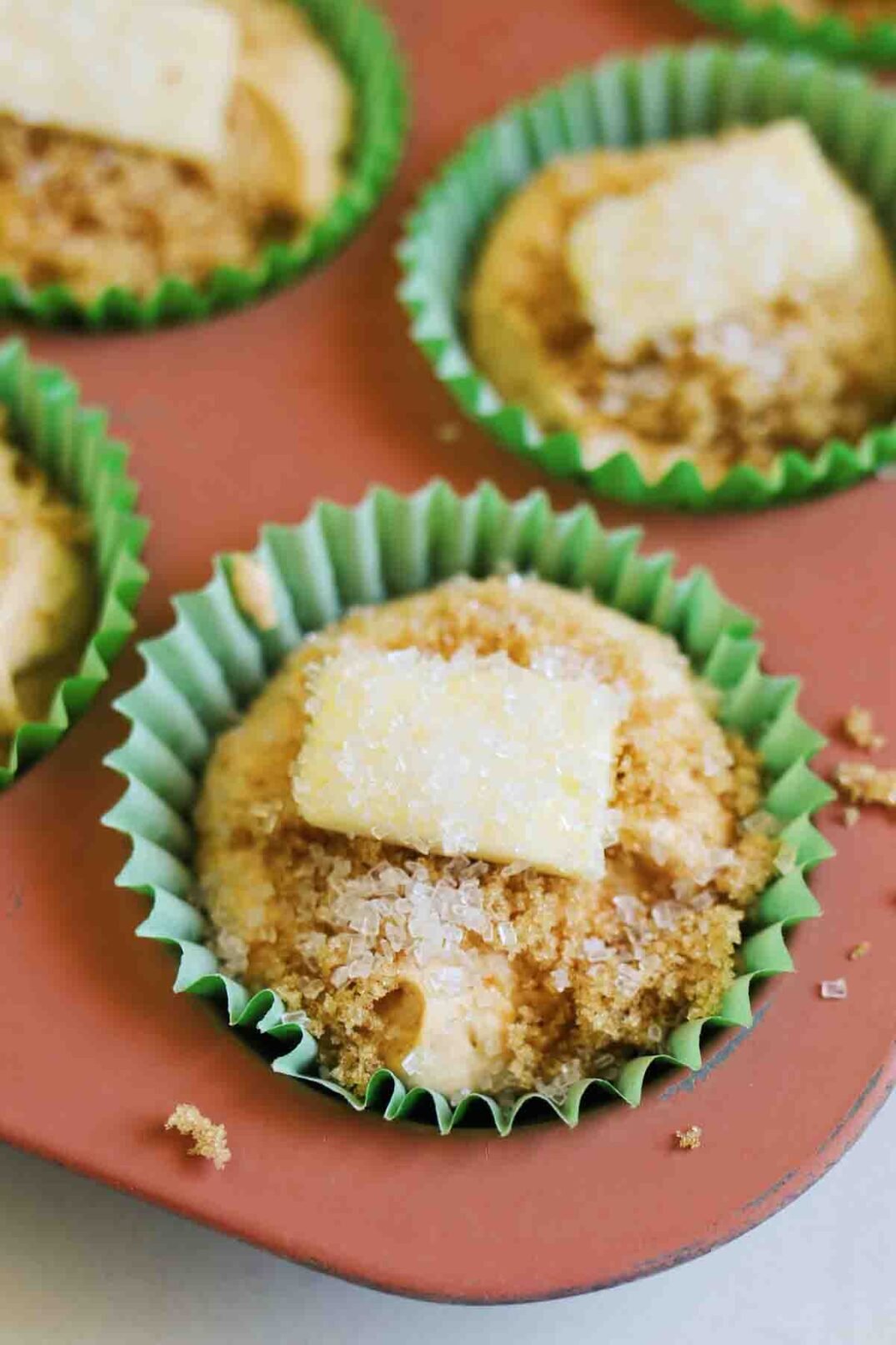 raw pumpkin muffins in a muffin tin with butter and brown sugar.
