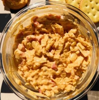 spicy pimento cheese dip on a black and white checkerboard cuttingboard.
