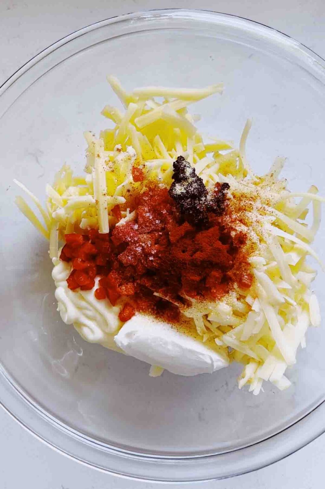 shredded cheese and peppers and spices in a glass bowl. 