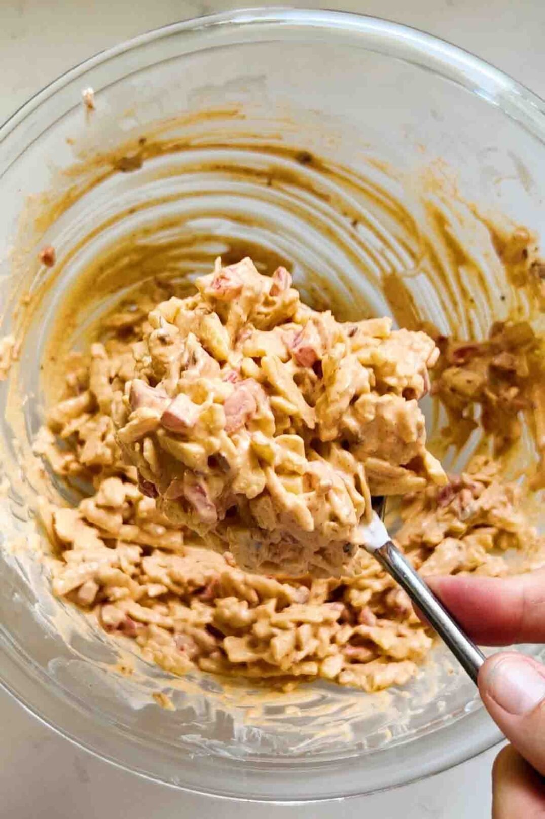 a spoonful of spicy pimento cheese dip in a glass bowl. 