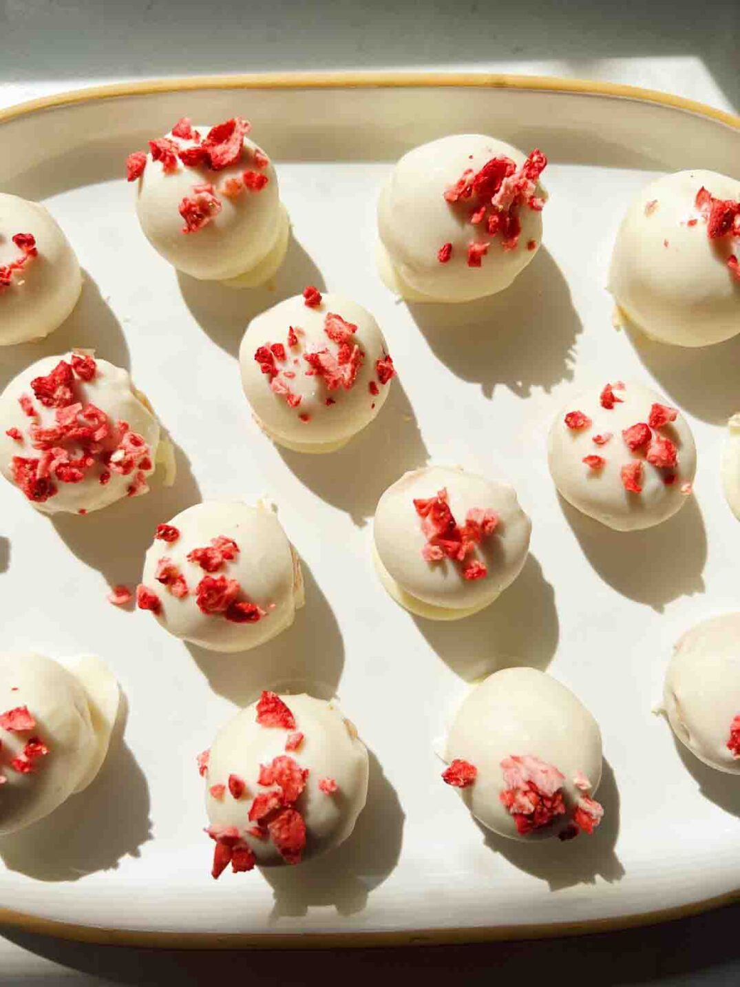 a white platter topped with a dozen strawberry shortcake oreo truffle balls.