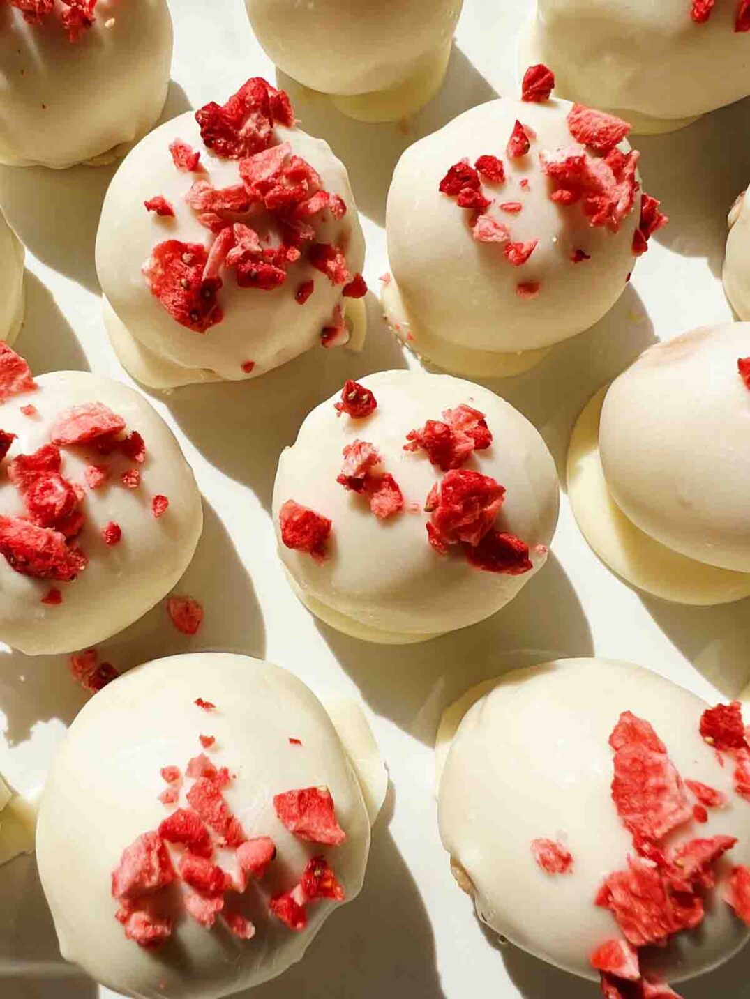 an up close view of a handful of strawberry shortcake oreo truffles.