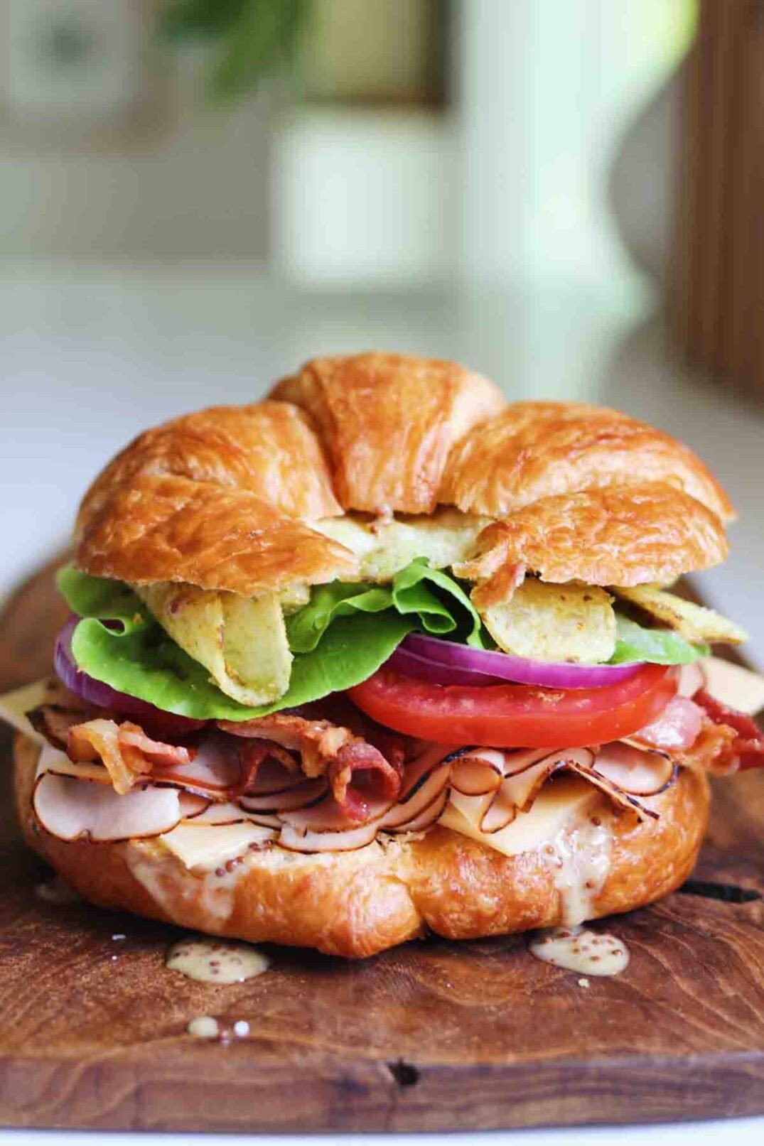 a croissant loaded with turkey, bacon, veggies and honey mustard.