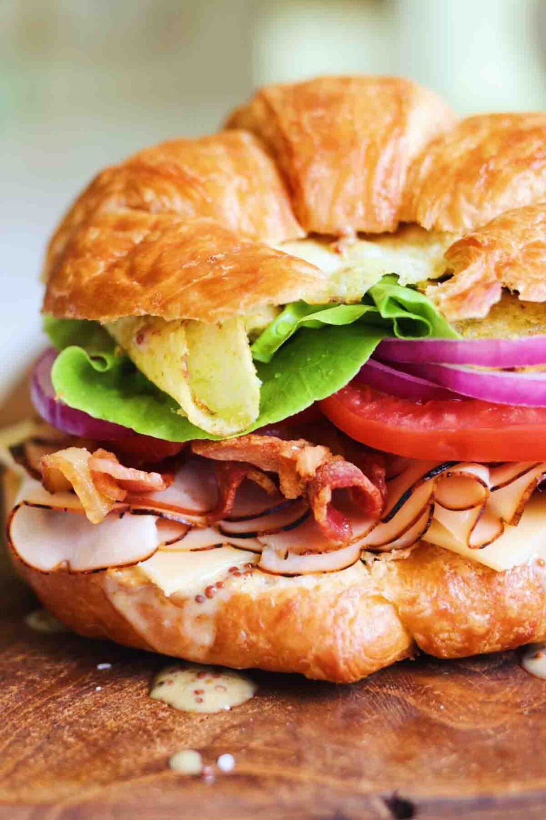 an up close view of a turkey croissant sandwich on a white surface. 