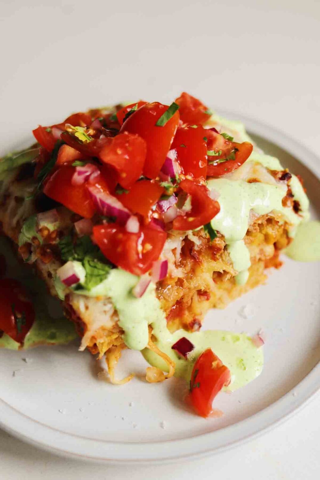 a white countertop with a piece of turkey pastelon, cilantro sauce and salsa.