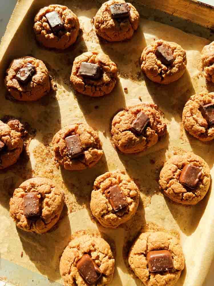 4 ingredient peanut butter cookies on a baking sheet lined with brown parchment paper.