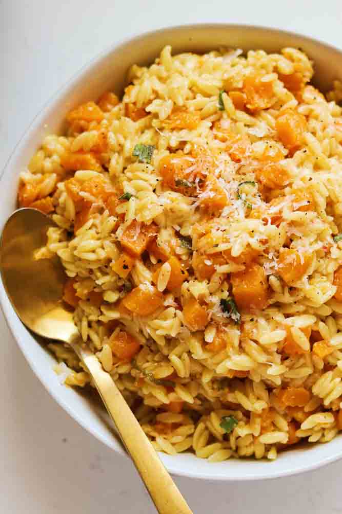 a white bowl filled with butternut squash orzo in brown butter sauce.