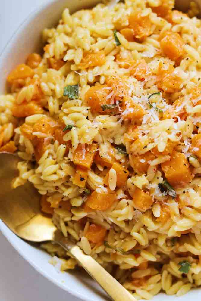 an up close view of a bowl filled with brown butter orzo with butternut squash and sage. 