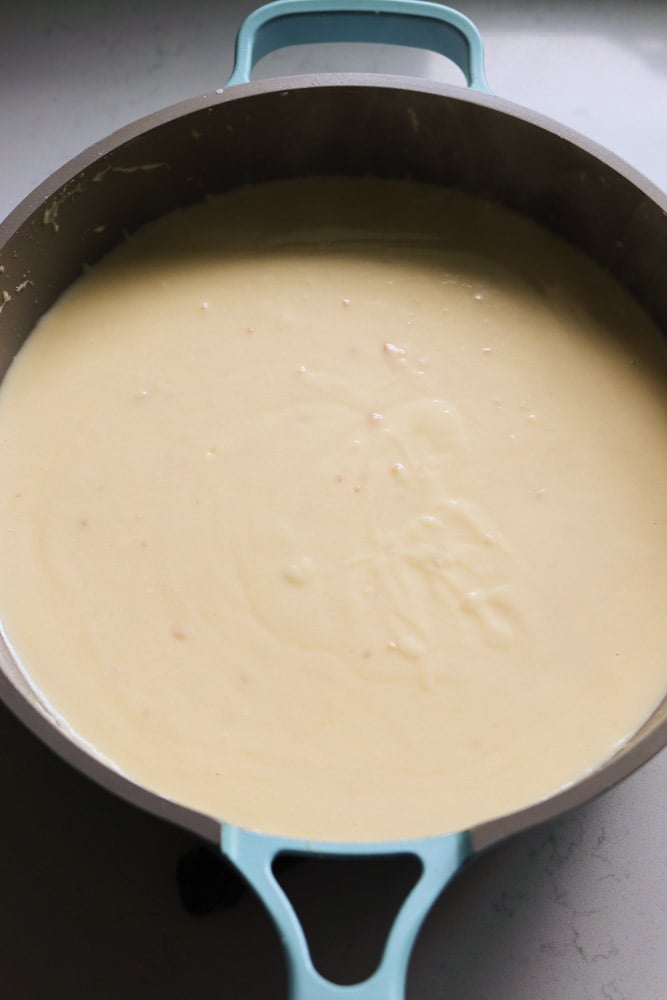 creamy white gouda cheese sauce in a blue sauce pan. 